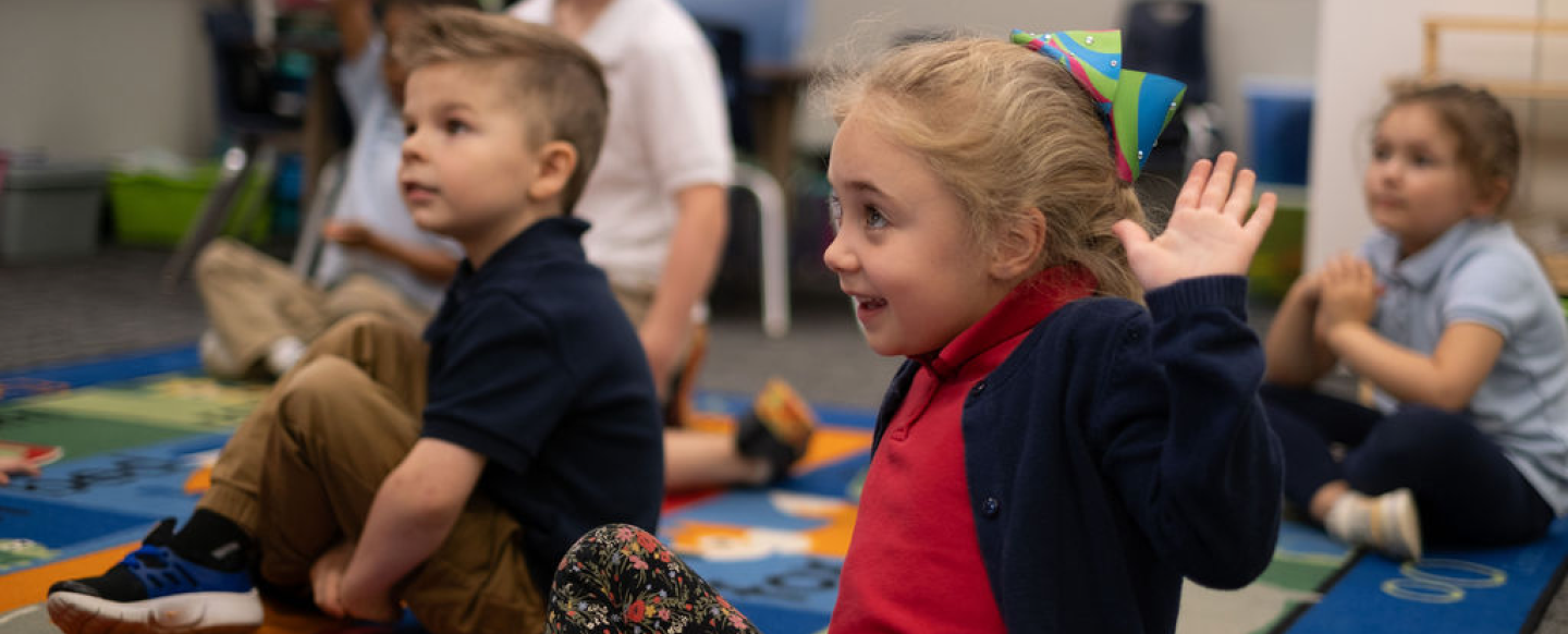 Girls smiling and raising her hand in class