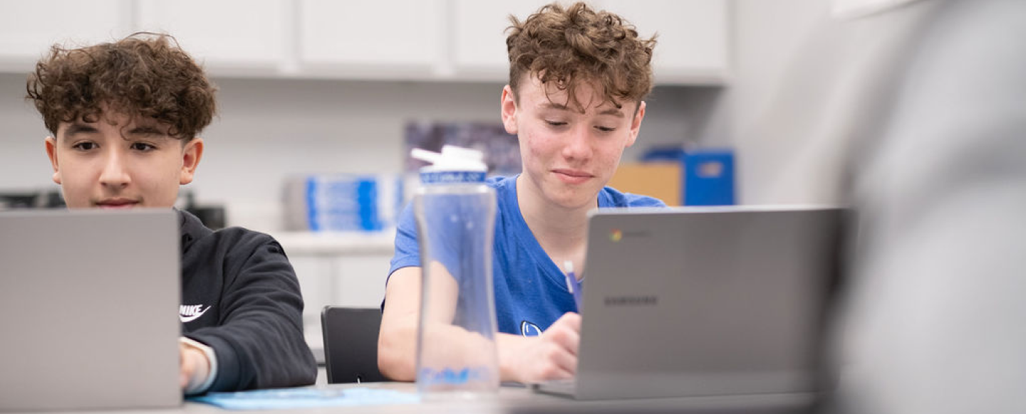 Two boys studying on their laptops