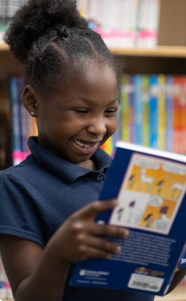 Girl smiling while reading in library